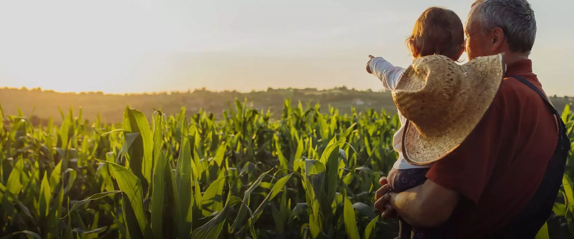 man holds a child and they are looking at sunset